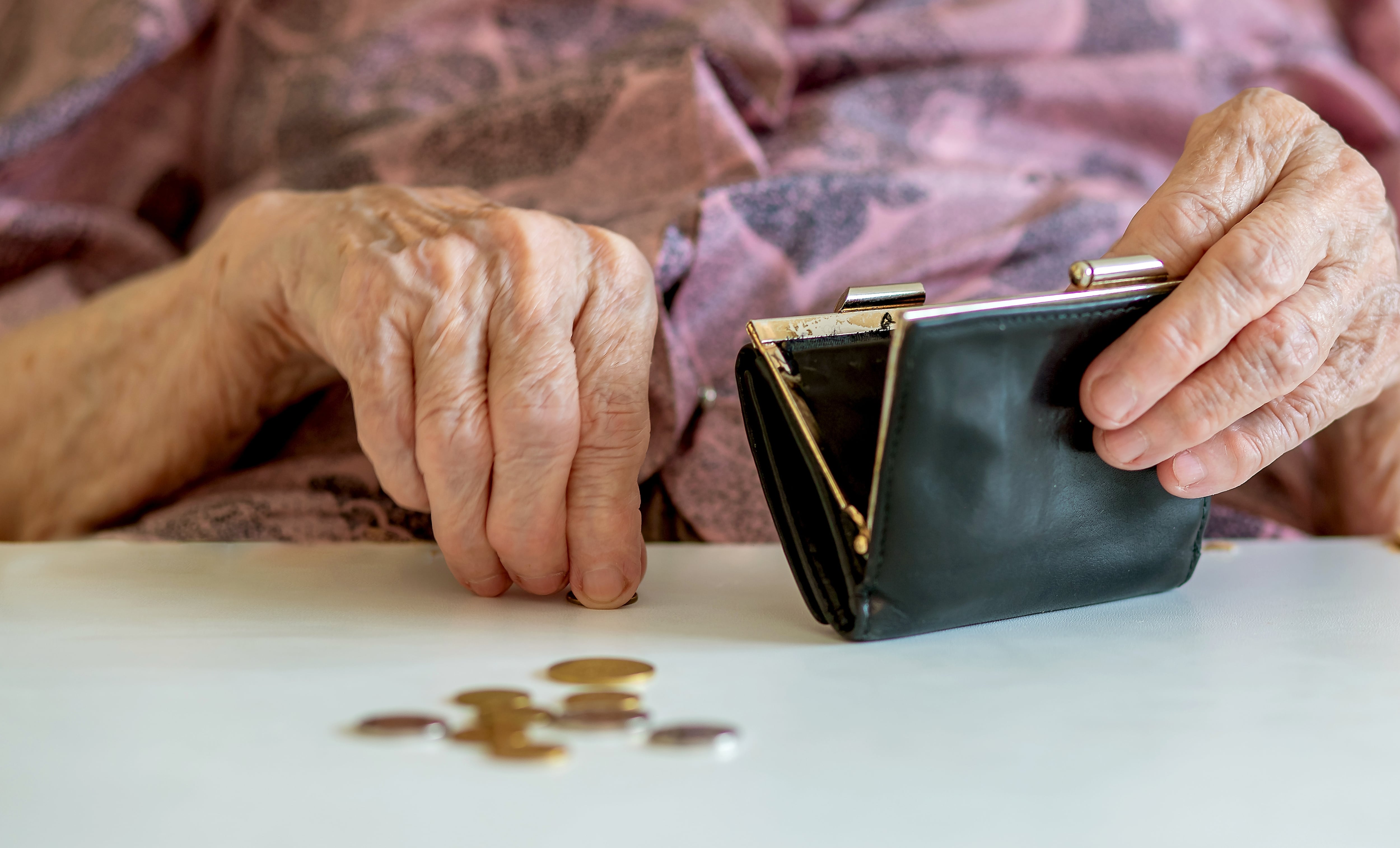 En la imagen, las manos de una adulta mayor contando monedas