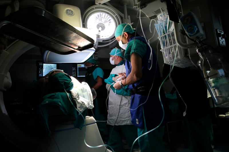 Quirófano casi a oscuras. La única luz es de la lámpara de cirugía, en el techo. Ilumina a dos médicos vestidos de verde.