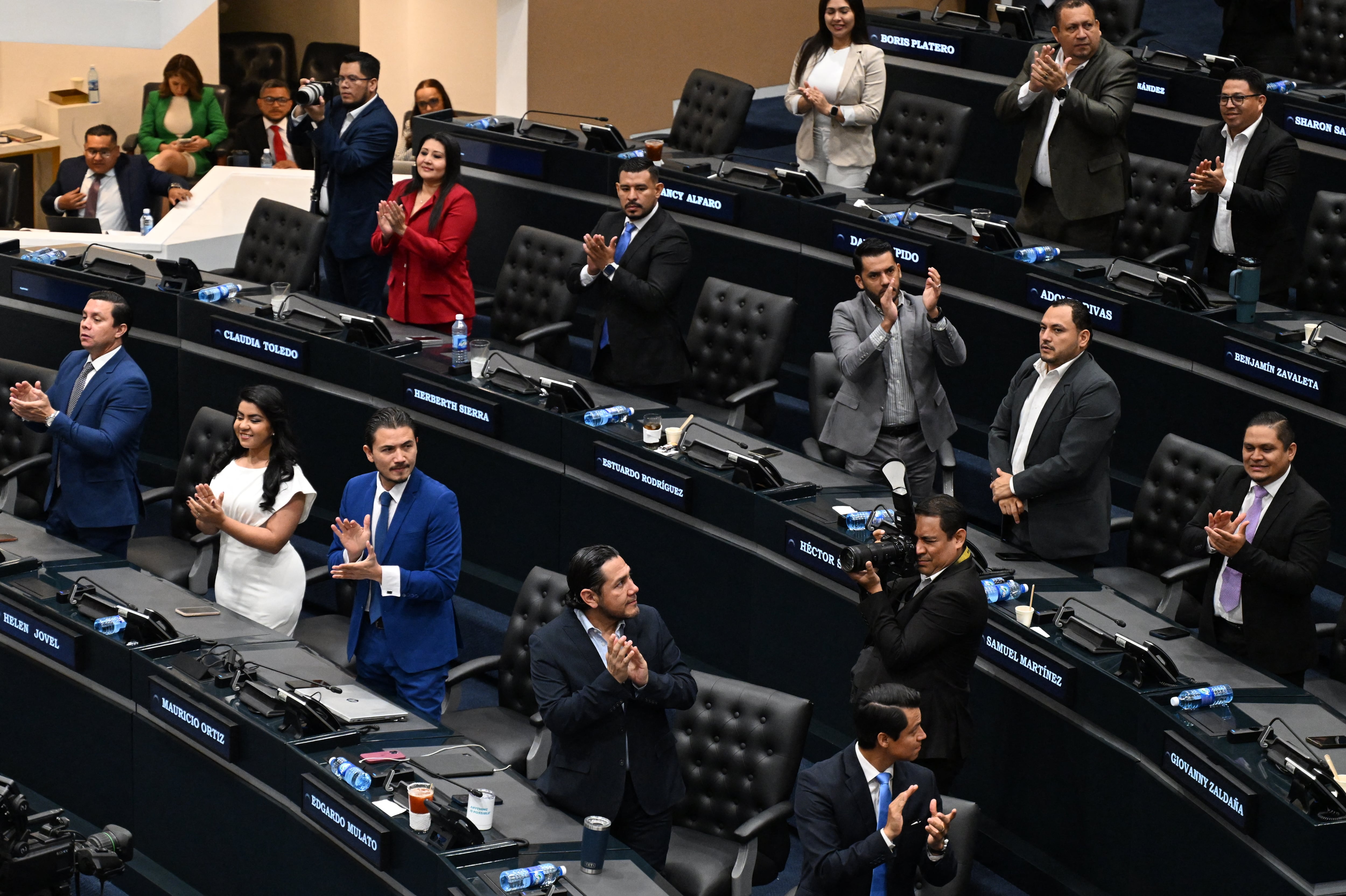 Deputies of the ruling New Ideas party celebrate after voting to ratify the constitutional reform to approve life imprisonment and extend the emergency regime to reach four years, at the Legislative Assembly, in San Salvador, on March 26, 2026. (Photo by Marvin RECINOS / AFP)