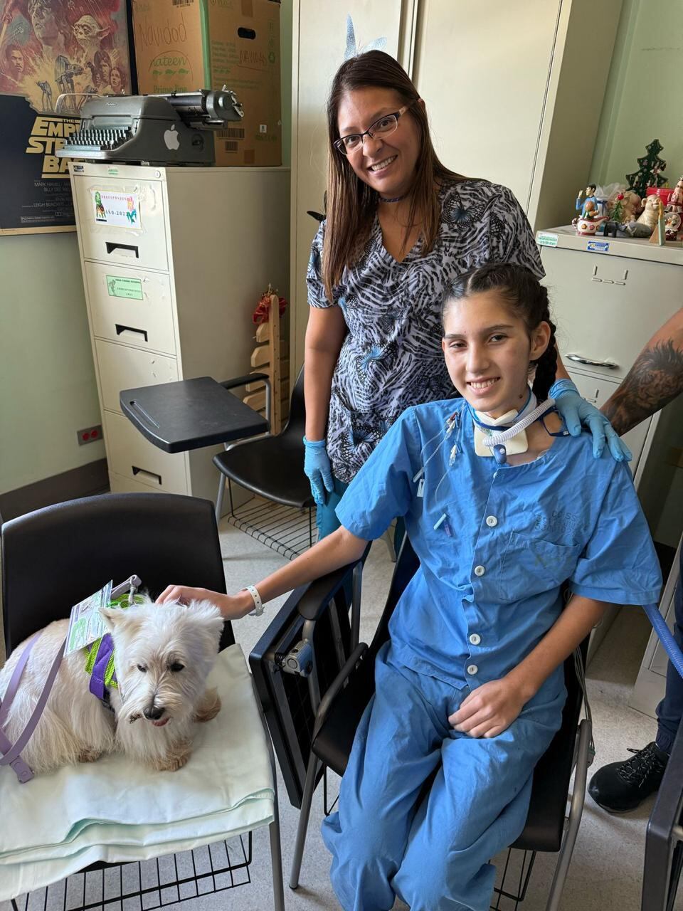Un perro de terapia en la sala de cuidados intensivos, una joven paciente y sus padres.
