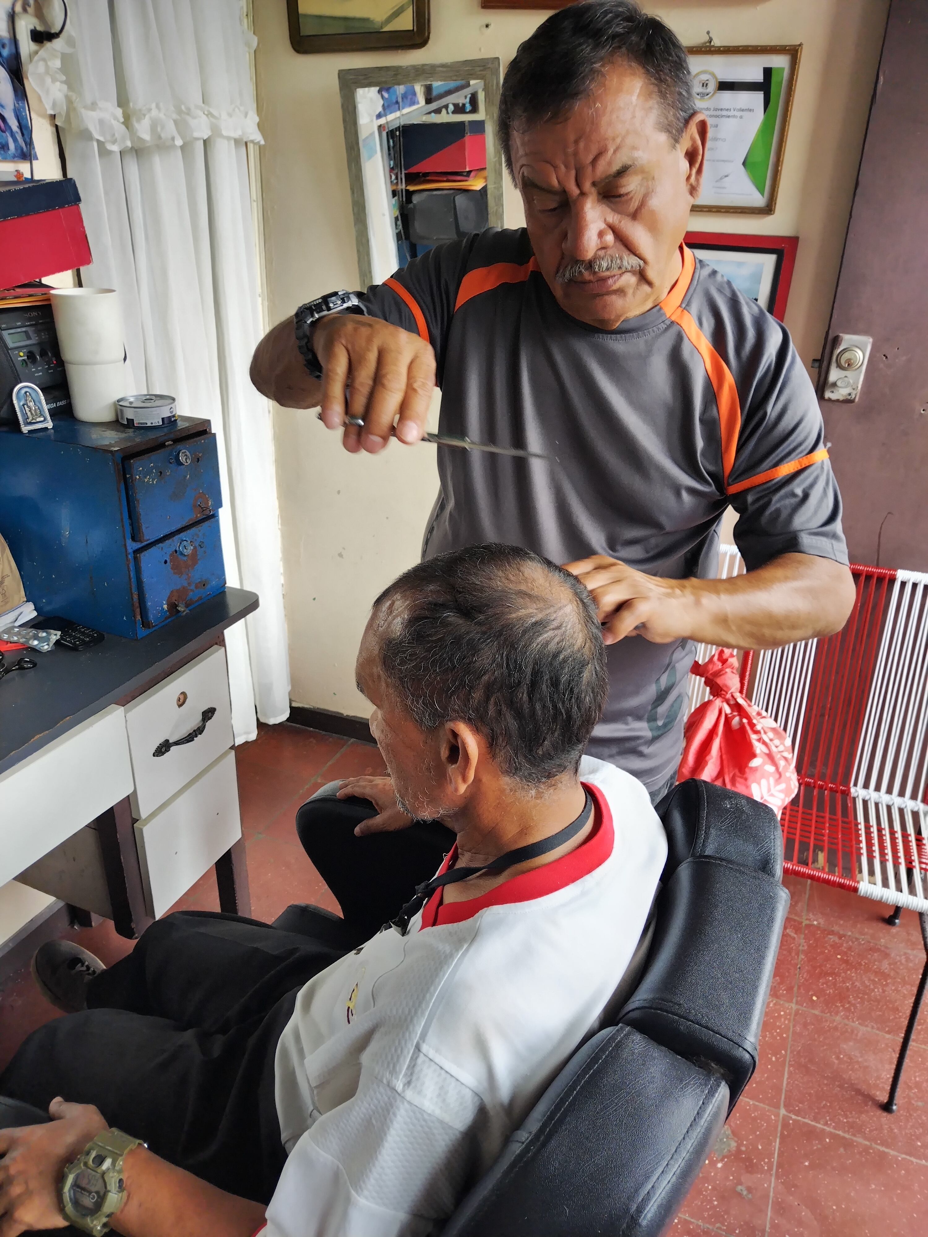 Giovanni Paniagua Araya es nacido, criado y actualmente vive en el barrio Cristo Rey de San José. Tiene 40 años de ser barbero y nos asegura que por más barberías que abran nuevas, con cortes super locos y llenos de diseños, su clientela no se le va