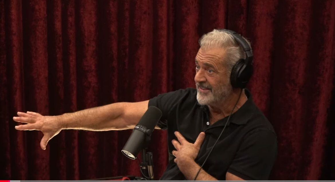 Mel Gibson en el podcast de Joe Rogan con audífonos y frente a un micrófono