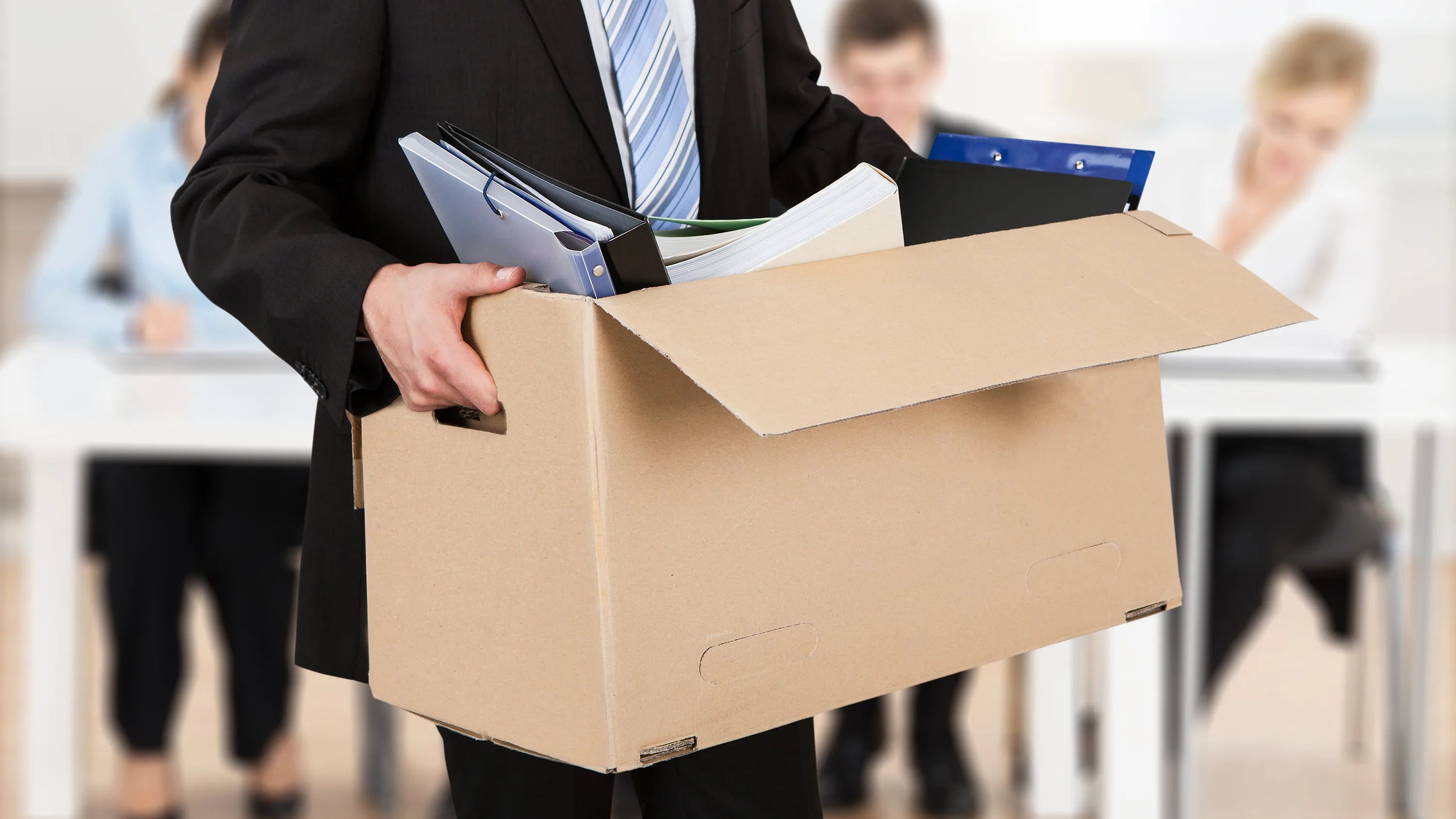 En la imagen una persona sosteniendo una caja con objetos de trabajo, con alusión a despido.