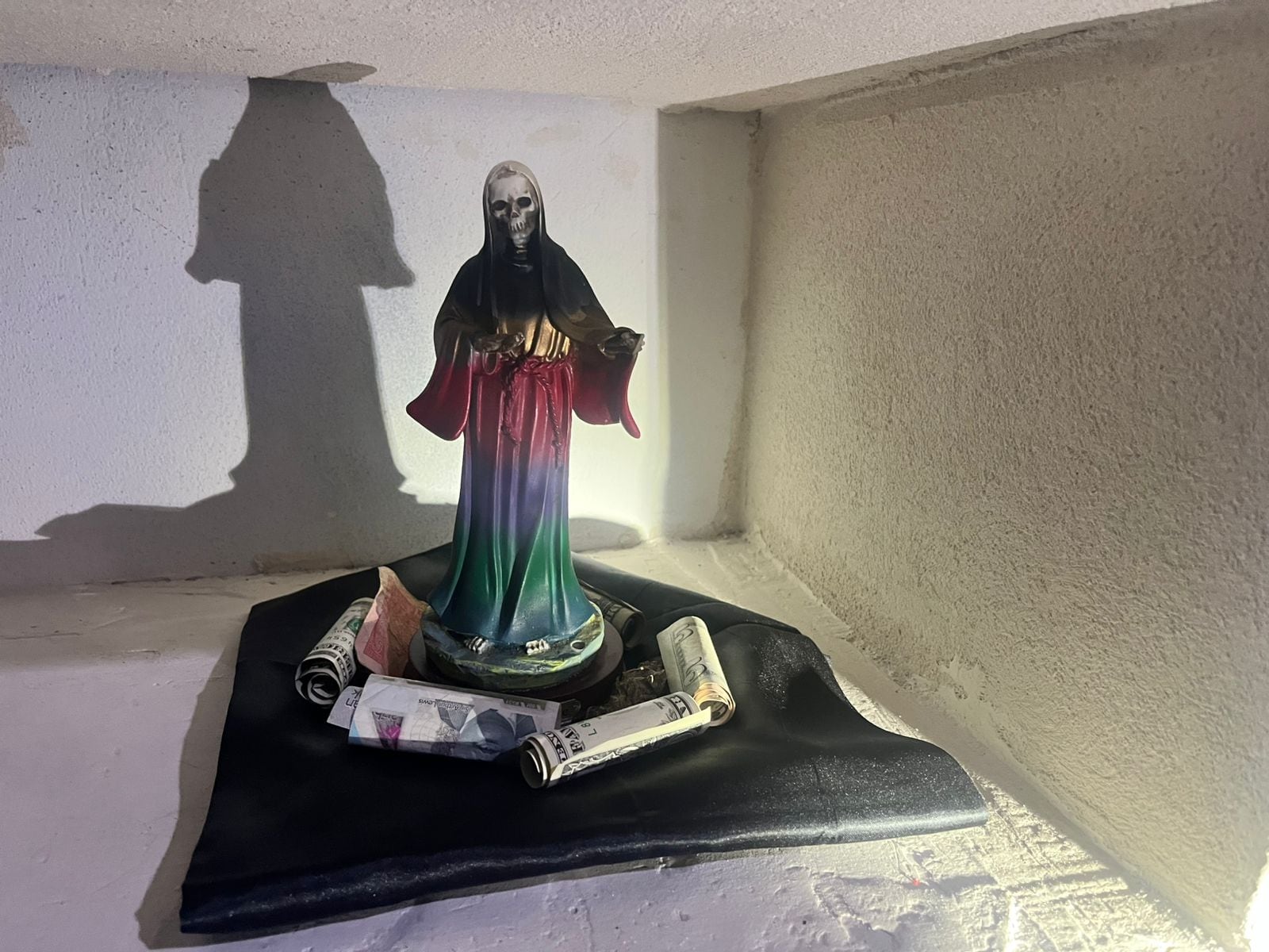 Entre los hallazgos en el sitio del operativo está una estatua a la Santa Muerte rodeada de dinero.